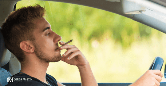 man driving a car smoking marijuana while behind the wheel