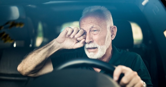 drowsy driver rubbing eyes
